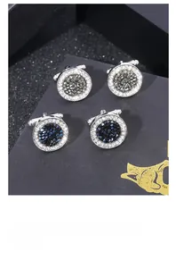 Dettaglio di gemelli tondi in argento con cristalli blu e grigi in confezione regalo