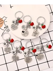 Vista detallada de llaveros plateados para profesores con dijes de manzana y corazón