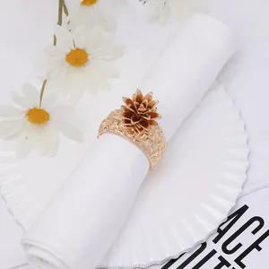 Detail of a golden pineapple napkin ring with embossed metal band on a white cloth