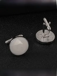 Dettaglio macro di gemelli tondi in metallo bianco su pelle nera con chiusura a scatto a T