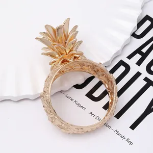 Golden pineapple napkin ring with textured finish on a minimalist tabletop setting