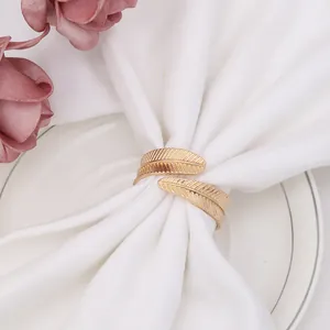 Close-up of golden feather napkin ring with detailed texture on a white plate