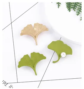 Close-up of elegant ginkgo leaf brooches with gold texture, green coating and pearls