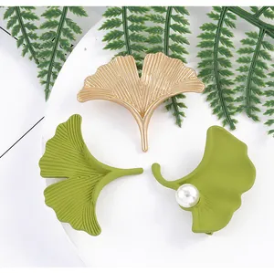Detail of ginkgo leaf hair clips in gold and green finishes with pearl accents