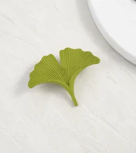 Macro detail of the matte green ginkgo leaf brooch showing delicate vein textures