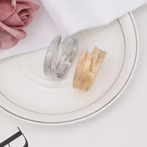 Detail of elegant leaf-shaped napkin rings in gold and silver finish on white porcelain