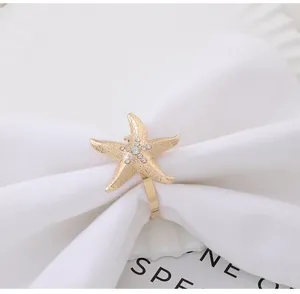 Detail of golden starfish napkin ring with white rhinestones on a white linen napkin