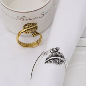 Elegant gold and silver feather napkin rings with brushed metal texture for table setting