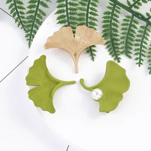 Elegant ginkgo leaf brooches in matte green and brushed gold with pearl accent