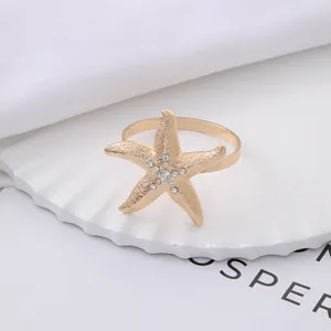 Golden starfish napkin ring with matte finish and rhinestones on a decorative plate