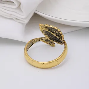 Close-up of vintage golden leaf napkin ring with metal texture on a white plate