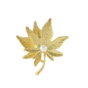 Golden maple leaf brooch with vibrant white pearl accent and detailed leaf veins