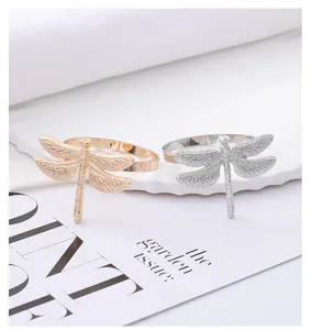 Detailed view of silver and gold dragonfly napkin rings with textured metal wings