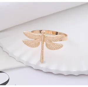 Close-up of golden dragonfly napkin ring showing detailed wing carvings on white tray