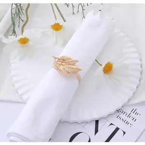 Macro detail of golden leaf napkin ring with intricate vein textures on white linen