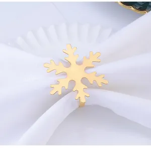 Primer plano de servilletero dorado de copo de nieve sobre plato blanco para la mesa