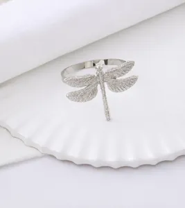 Macro shot of silver dragonfly napkin ring with detailed wings on a white ceramic plate
