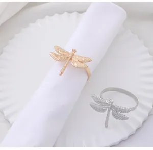 Close-up of gold and silver dragonfly napkin rings with detailed wing texture on white plate