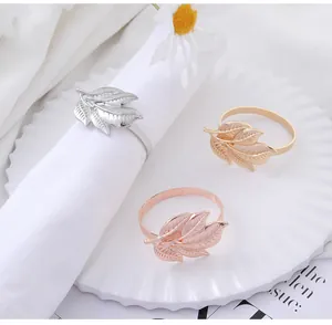 Detailed view of elegant leaf-shaped metal napkin rings in gold, silver, and rose gold