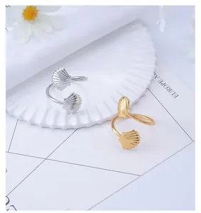 Macro detail of fan-shaped shell napkin rings with gold and silver polished metal textures