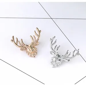 Macro detail of stag head brooches showing intricate gold and silver plated metal textures