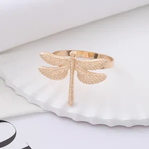 Elegant gold metal dragonfly napkin ring with textured wings on a white base decor