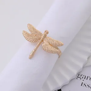 Golden dragonfly metal napkin ring with embossed wings on a white fabric napkin