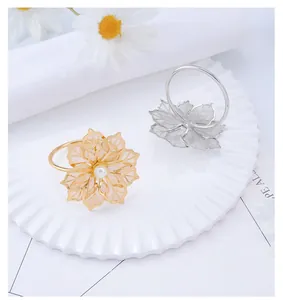 Detailed view of gold and silver metal flower napkin rings with elegant pearl centers