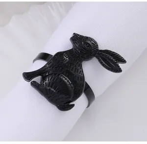 Detail of a black alloy bunny napkin ring with embossed texture on white fabric