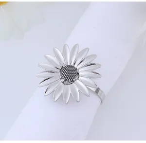 Detailed close-up of a silver sunflower napkin ring on a white cloth for table decor