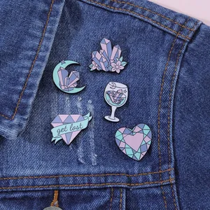 Detail of five purple crystal enamel pins styled on a blue denim jacket texture