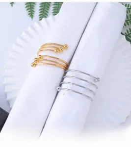 Modern spiral metal napkin ring with ball ends shown on a white napkin with a plate