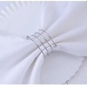 Detail of silver spiral metal napkin ring with beads on a white decorative plate