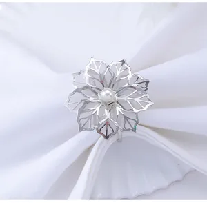 Detail showing an elegant silver flower napkin ring with hollow petals and a pearl center