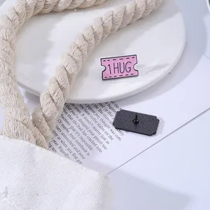 Detail van emaille stempelspeld met '1 HUG' tekst en achteraanzicht van sluiting