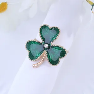 Golden four-leaf clover napkin ring with green enamel and crystal on white cloth