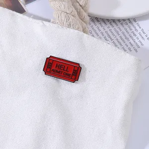 Detail van rode HELL ADMIT ONE emaille speld op een witte canvas tas van stof