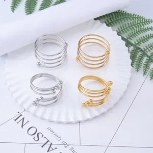 Set of 4 gold and silver spiral metal napkin rings with beads on white ceramic plate