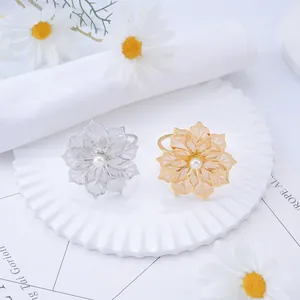 Elegant gold and silver metal flower napkin rings with pearls on a white plate