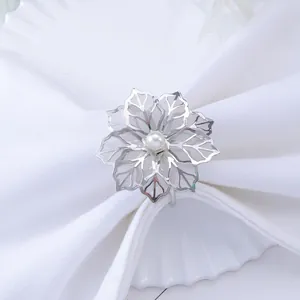 Silver flower napkin ring with hollow mesh petals and a central pearl on a white napkin