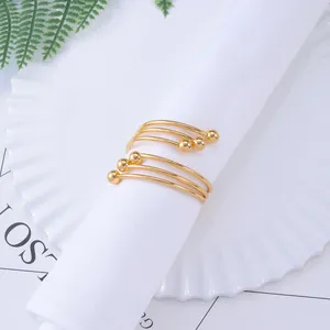 Elegant gold spiral metal napkin ring with ball ends on a white napkin and ceramic plate