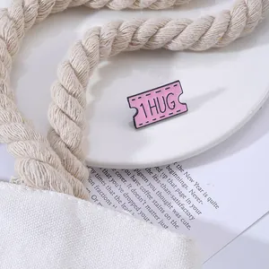 Roze emaille ticket speld met 1 HUG tekst op stijlvolle witte canvas tas achtergrond