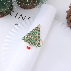 Golden Christmas tree napkin ring with green enamel and rhinestones on a holiday table