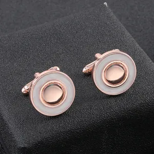 Gros plan de boutons de manchette ronds or rose avec incrustation blanche sur fond noir