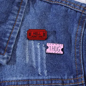 Detailopname van HELL ADMIT ONE emaille speldjes op een blauwe denim stoffen textuur