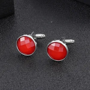 Detailed close-up of round red gemstone cufflinks with a polished silver-tone finish