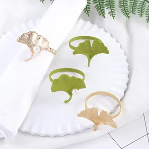 Servilleteros de hoja de ginkgo verde y oro con perlas en vajilla blanca elegante