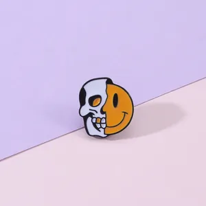 Vue macro détaillée de broches en émail avec un design divisé de crâne blanc et visage souriant