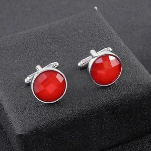 Close-up of classic silver cufflinks with round red faceted gems on black background