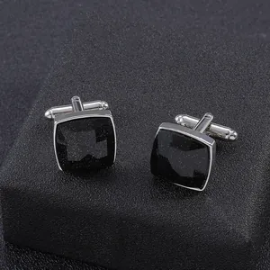 Macro detail of men's square silver cufflinks with faceted black stone and T-bar clasp